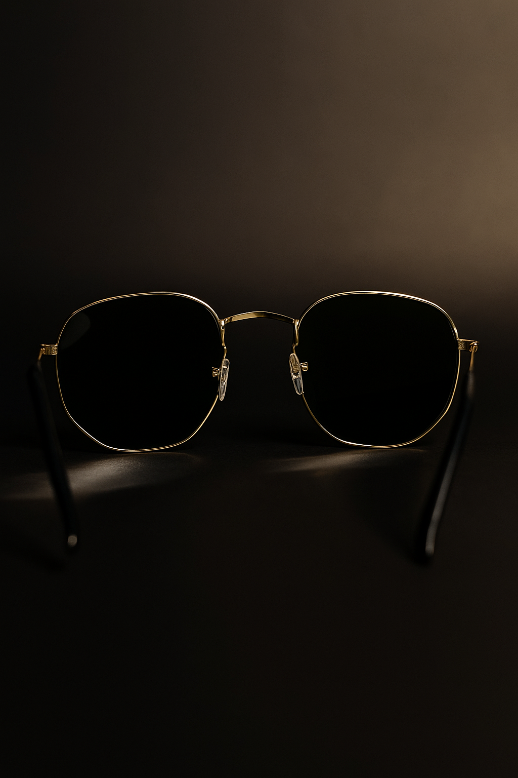 Sunglasses with gold frame and dark lenses on a black background