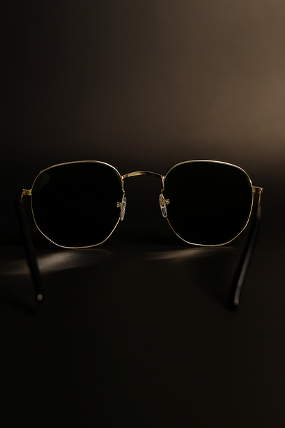Sunglasses with gold frame and dark lenses on a black background